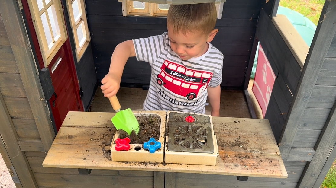 Toddler playing in mud kitchen with pots and dirt backyard sensory activity